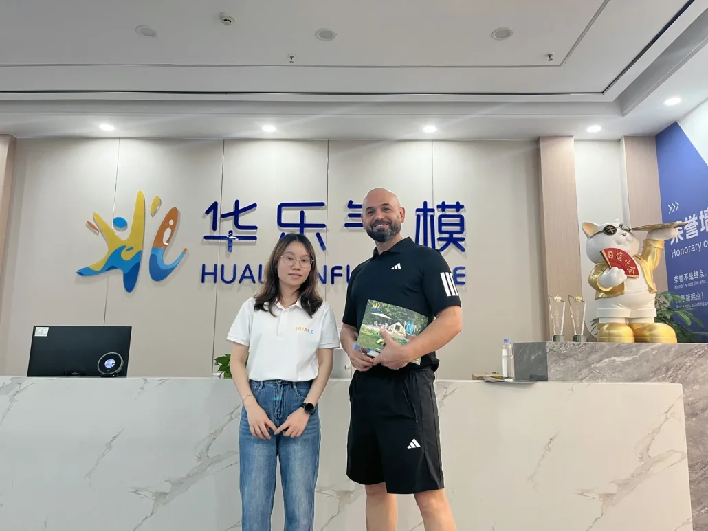 Two people standing in front of the Huale reception desk with a large ornamental cat figure in the background.