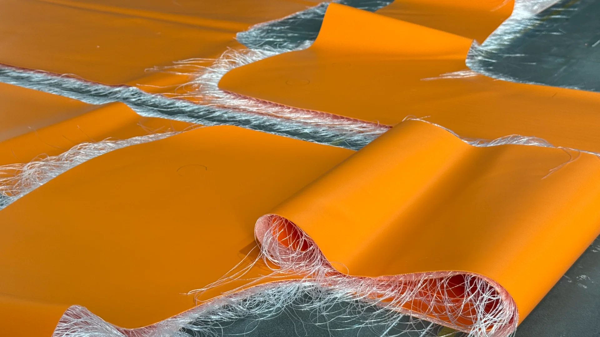 Orange fiberglass composite material with visible fibers and smooth texture on a flat surface.