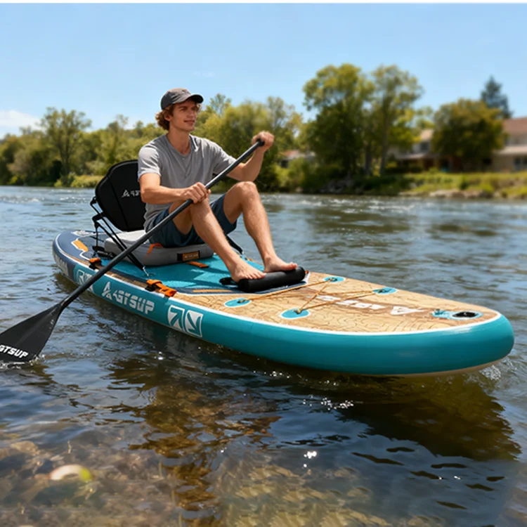 Man wearing a cap and t-shirt paddleboarding on a calm river under a clear blue sky, surrounded by lush greenery.
