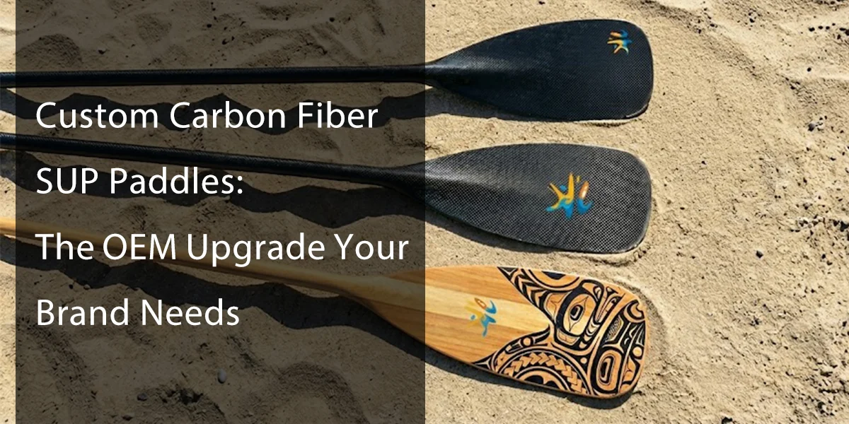 Three custom SUP paddles featuring carbon fiber and wood designs with logos on a sandy beach.