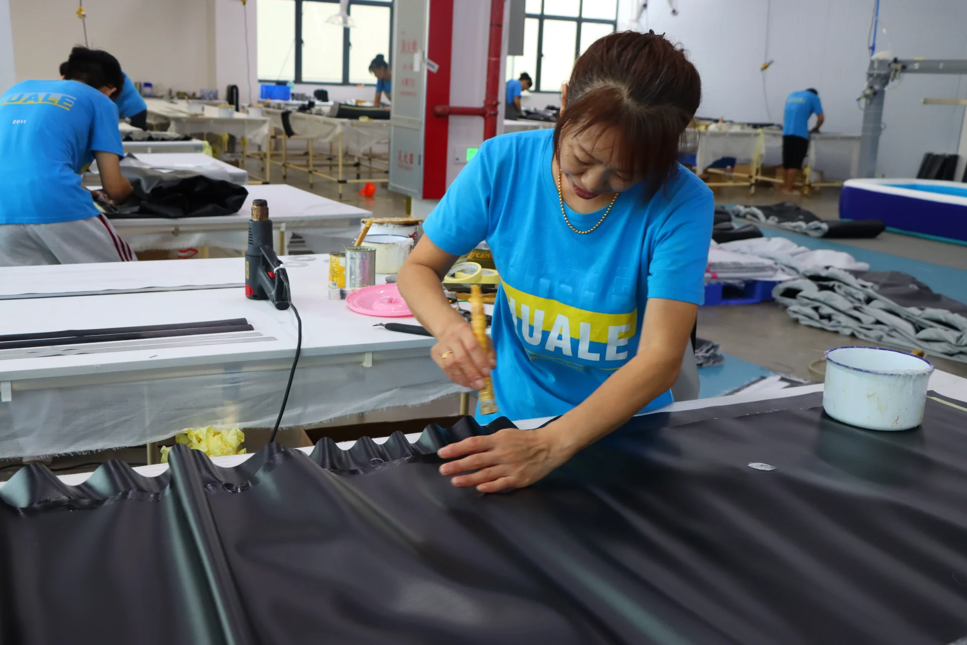 Professional workers crafting and assembling fabric garments at a spacious workshop with tools and materials around.