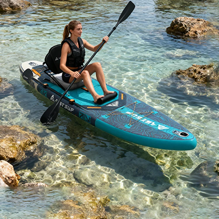 A woman in a life vest paddleboarding on a turquoise inflatable board over clear, shallow water with visible rocks.