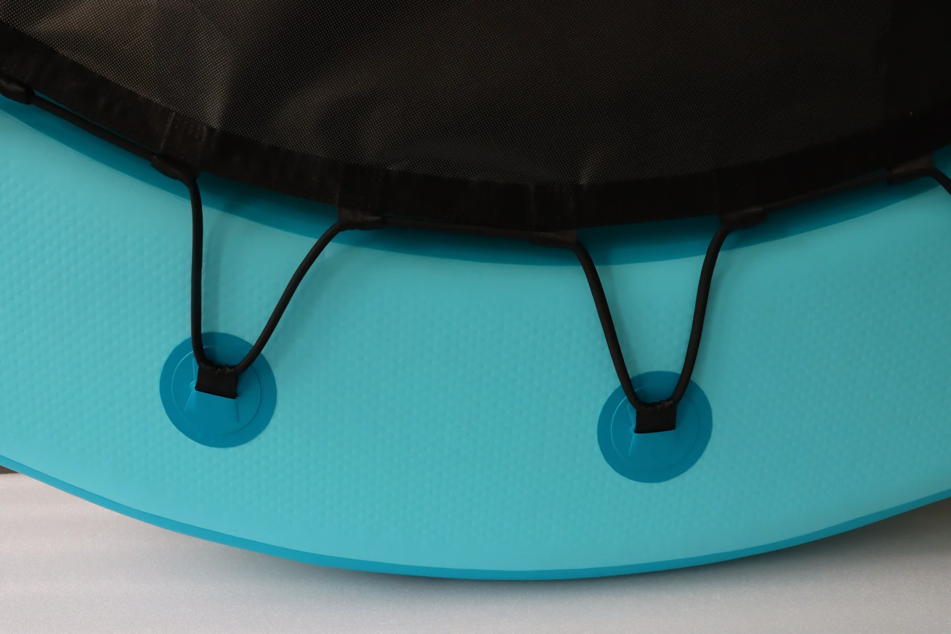 Close-up of a blue paddleboard deck featuring black bungee cords attached to it.