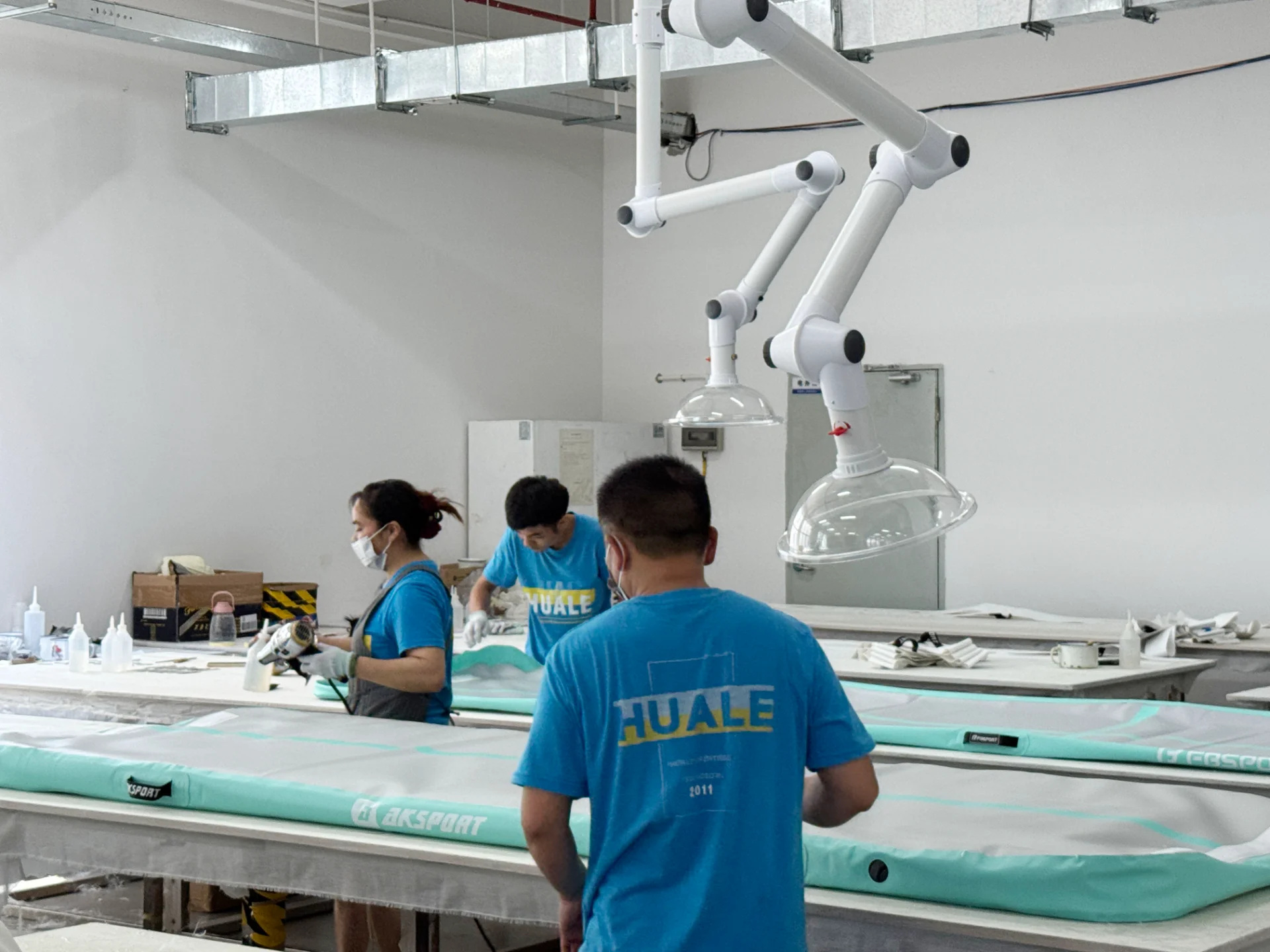 Workers in a factory assembling inflatable products on tables.