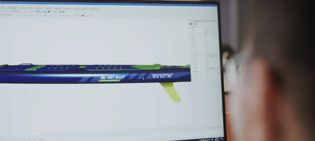 Computer screen showing 3D CAD design of a blue and green stand-up paddle (SUP) board with dimensions and branding.