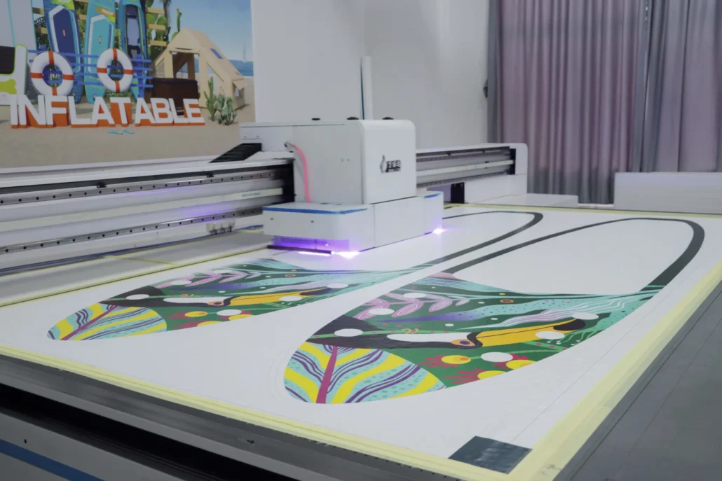 Digital printer producing a colorful design on a large sheet in a workshop with signage in the background.