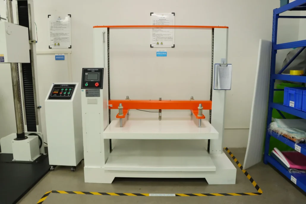 Packaging compression testing machine with control panel in an industrial lab setting, equipped with safety markings on the floor.