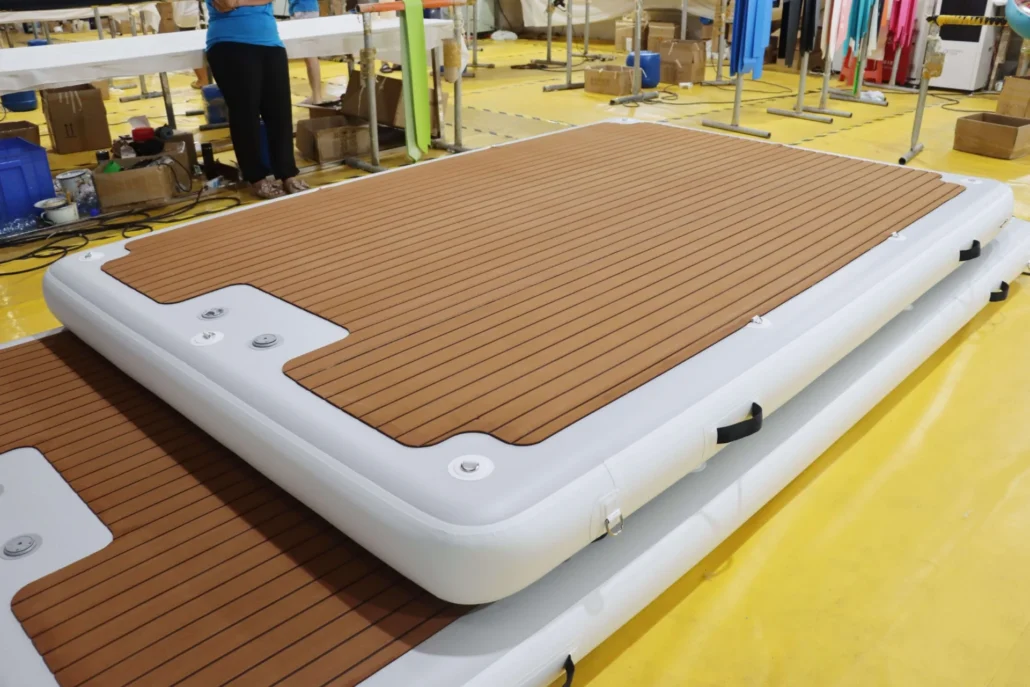 Inflatable denim platform with wooden design in a factory, surrounded by boxes and fabric rolls. Workers are visible around.