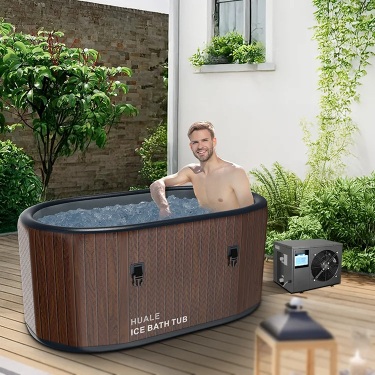 A man sitting in a Huale ice bath outdoors surrounded by greenery, with a cooling unit nearby on a wooden patio.