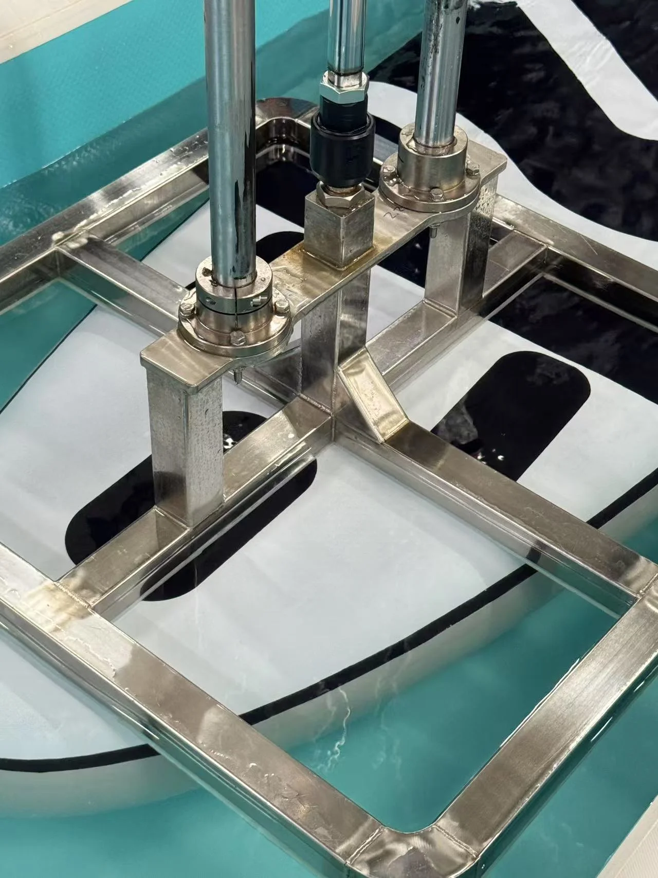 Close-up of a metal frame with vertical tubes on a blue and white surface, showing detailed construction elements.