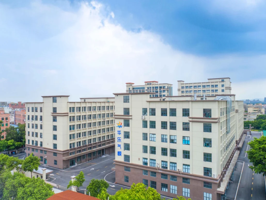 Aerial view of a modern industrial building complex with multiple stories and beige facade under a blue sky with clouds.