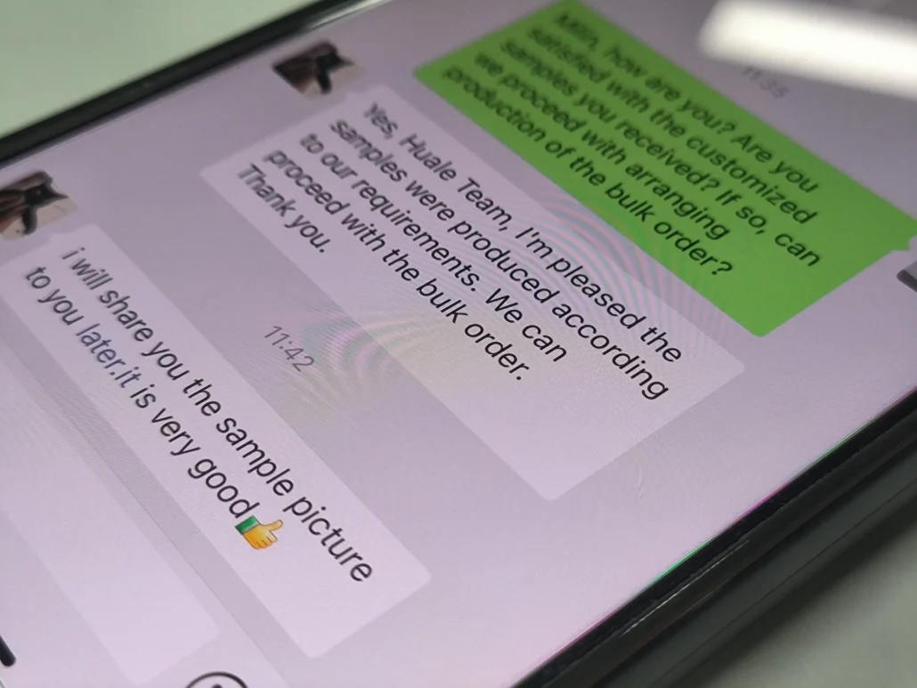 Close-up of a smartphone screen displaying a professional chat conversation about bulk orders and sample approval.