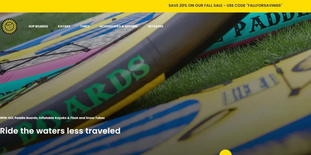 Close-up view of colorful SOL paddleboards on grass with promotional text about a fall sale offering 20% off.