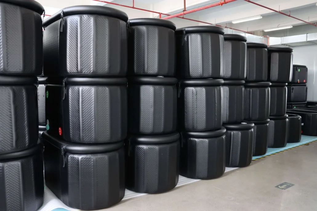 Several large, black storage containers stacked in a warehouse with a visible futuristic design.