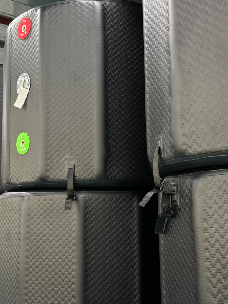 Close-up of stacked industrial tanks with a textured surface, various control buttons and straps visible.