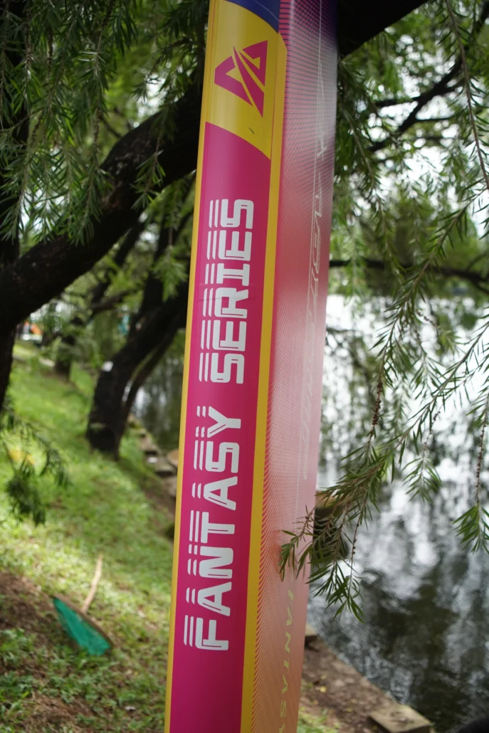 Close-up of a Fantasy Series banner with vibrant colors in an outdoor setting surrounded by trees and a lake.