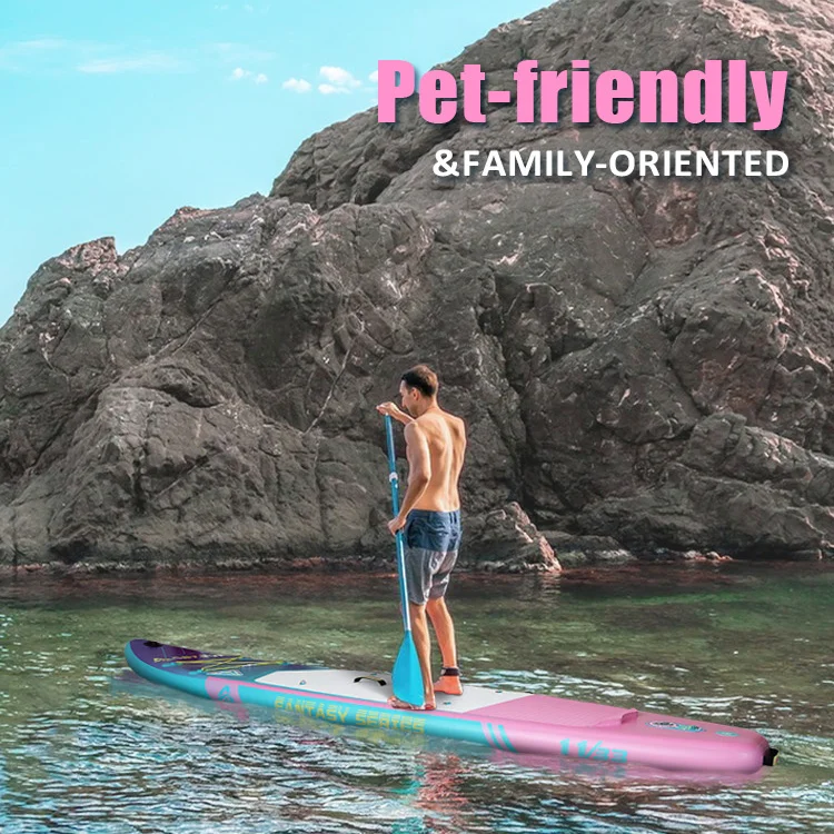 Man standing on a colorful paddleboard near a rocky coastline under clear blue skies, promoting a pet-friendly and family-oriented vibe.