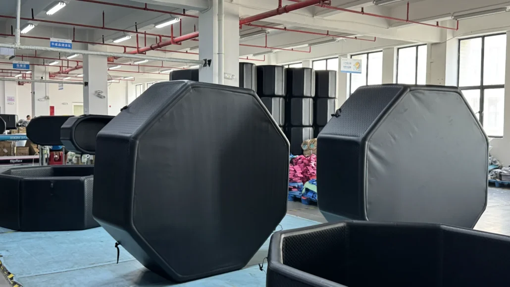 Large octagonal black padded structures in a well-lit factory space with industrial lighting and storage in the background.