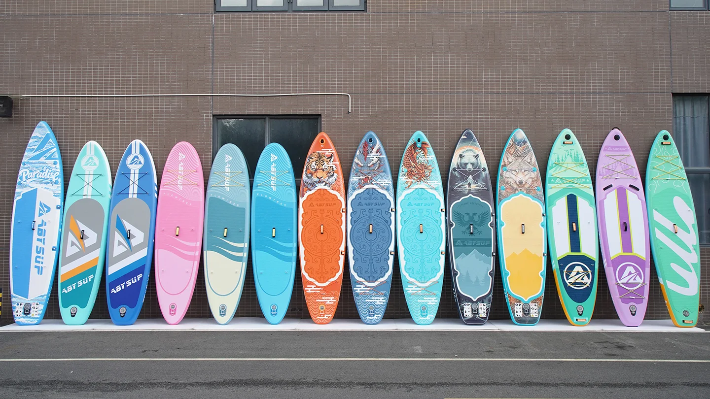 A collection of colorful paddleboards with various designs standing upright against a tiled wall in an urban setting.